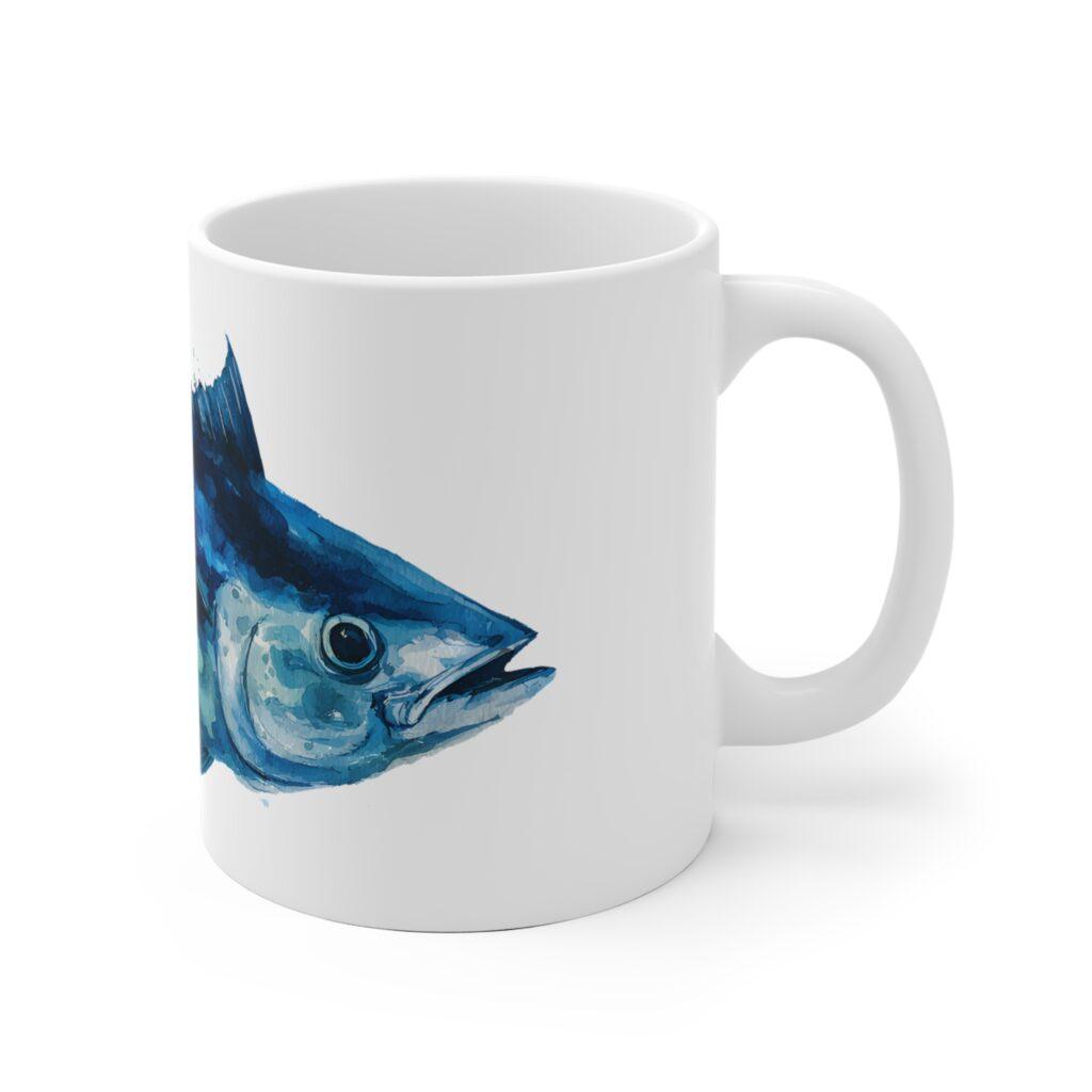 Eine wei&szlig;e Keramiktasse mit blauem Thunfisch im Aquarellstil bringt maritimes Flair und ein markantes Fischmotiv auf den Fr&uuml;hst&uuml;ckstisch.